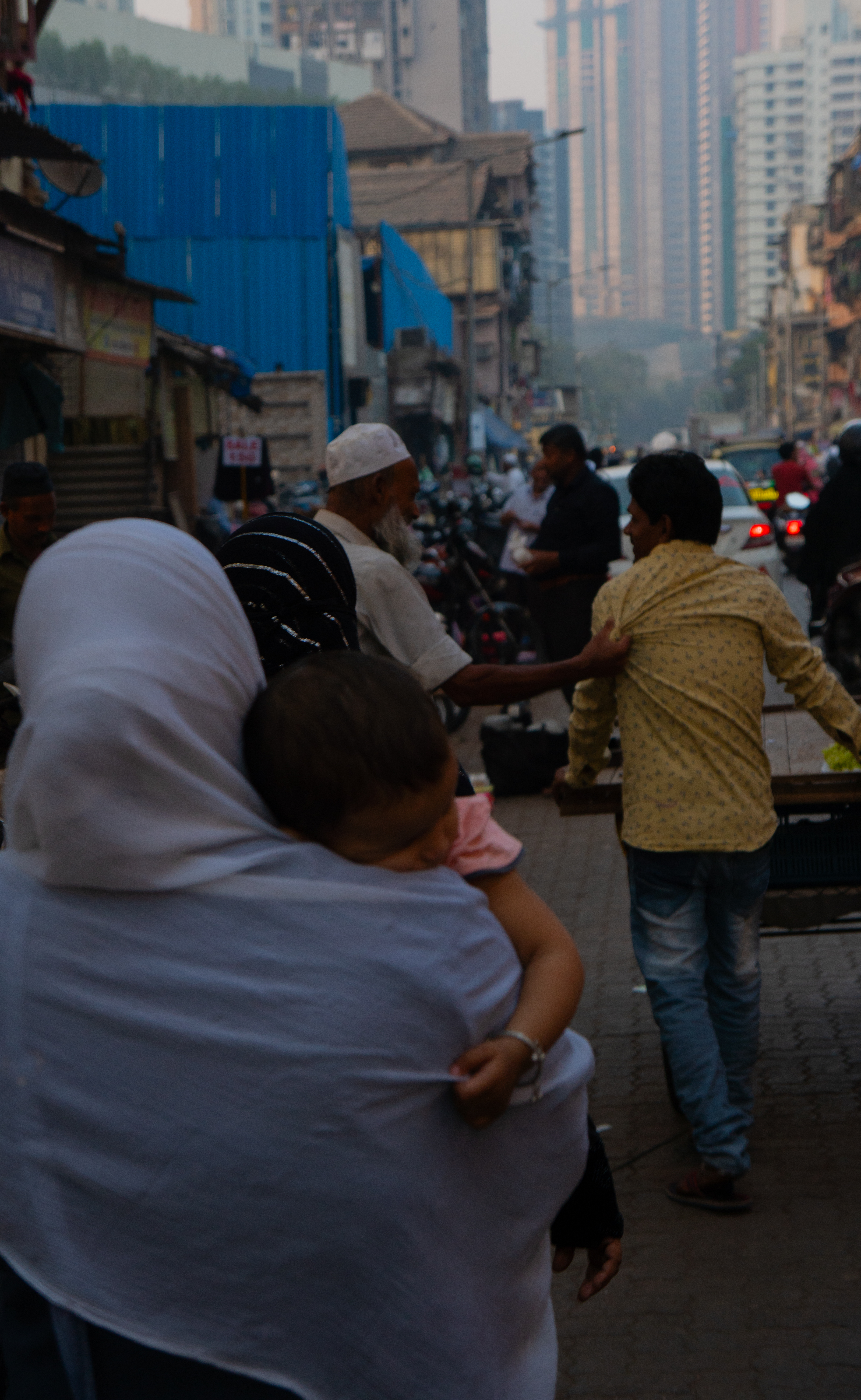 Mom holding kid in busy street in Mumbai
