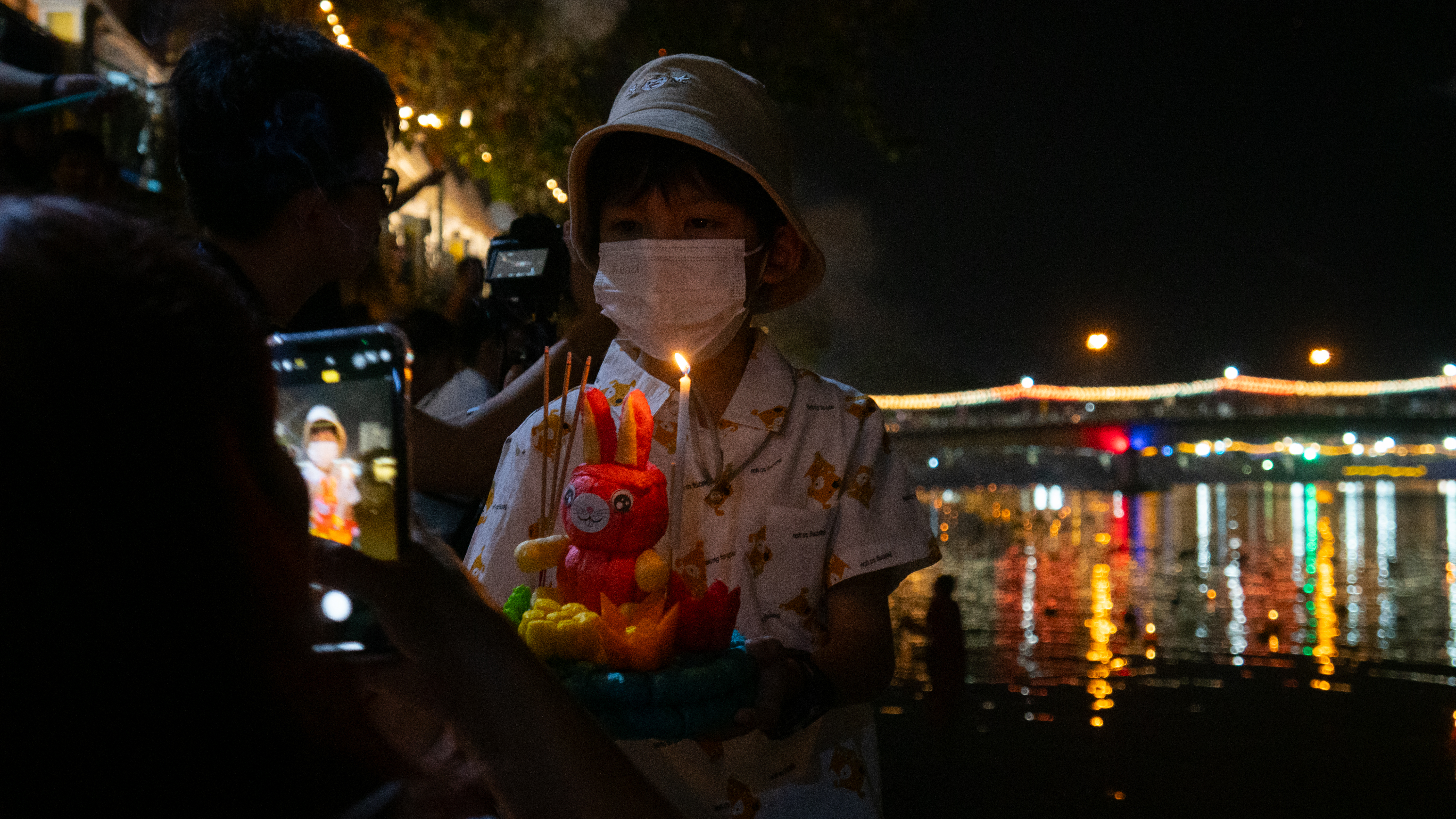 Child getting photographed near river in Thailand