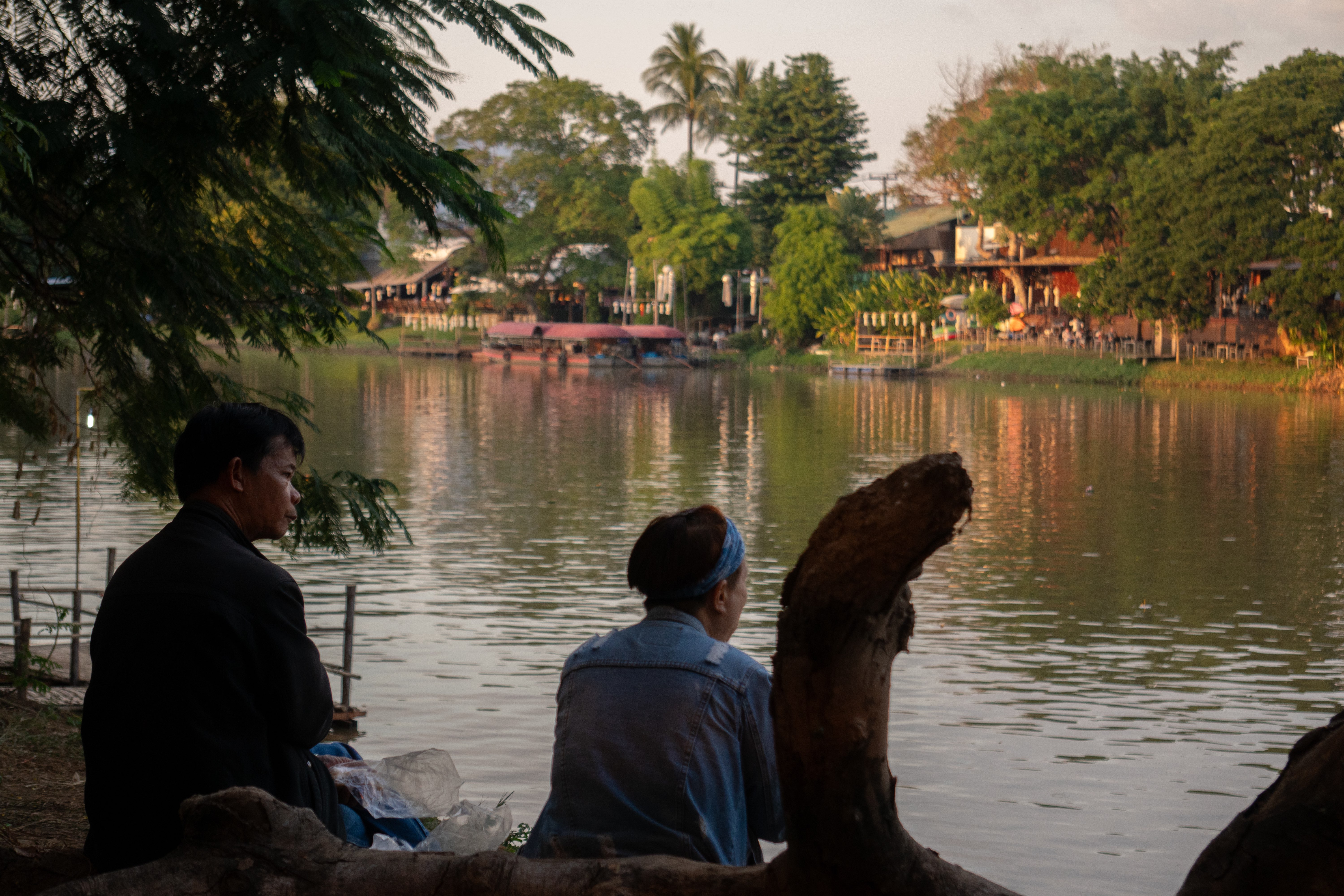 Two people sitting near river in Thailand